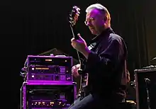 Robert Fripp ergonomically plays electric guitar while sitting in a posture developed through years of application of the Alexander Technique.